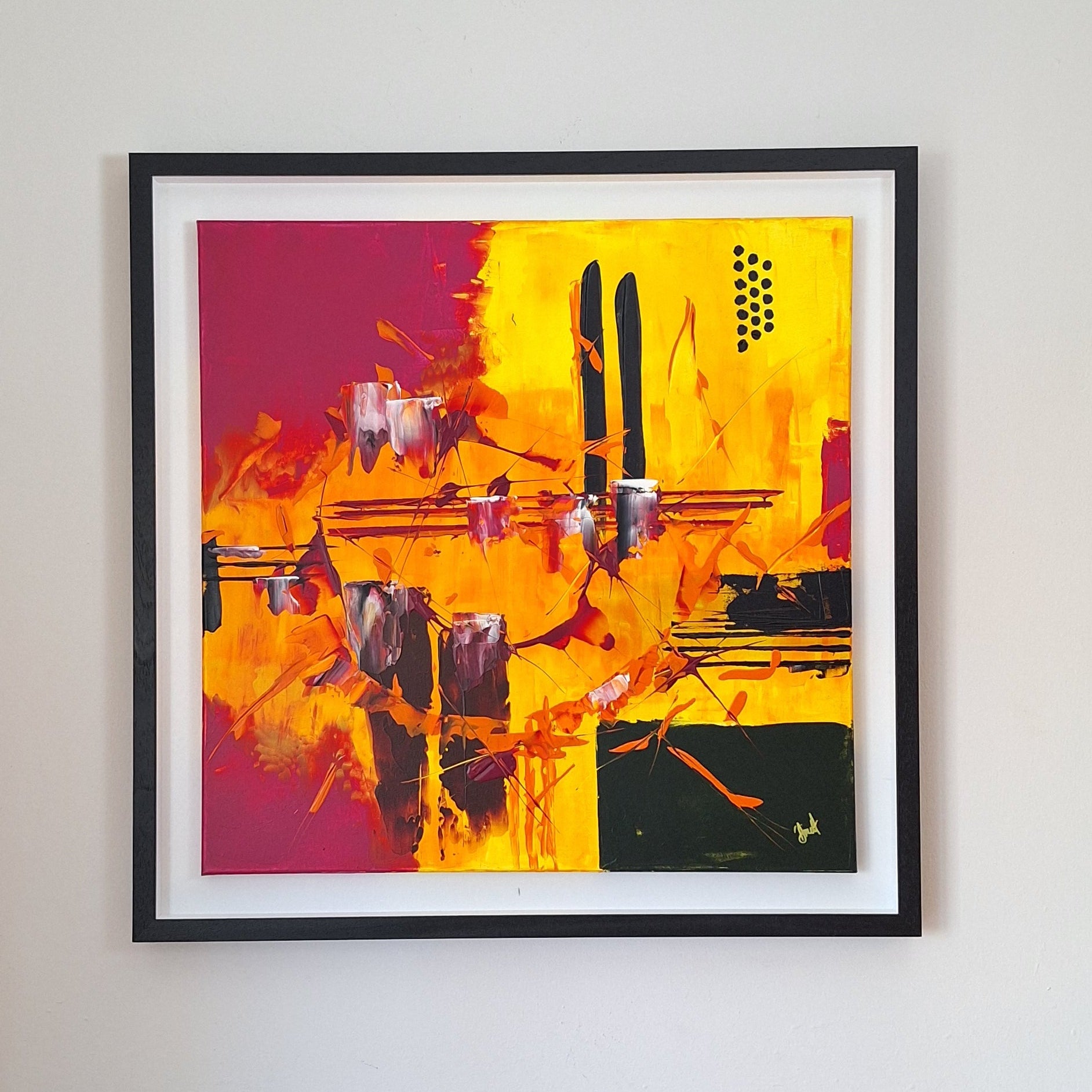 Framed abstract artwork by Irish artist Áine Hayes with vibrant colors on a white wall